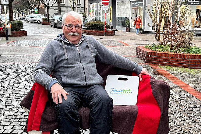 Ein älterer Mann sitzt auf einer Bank.