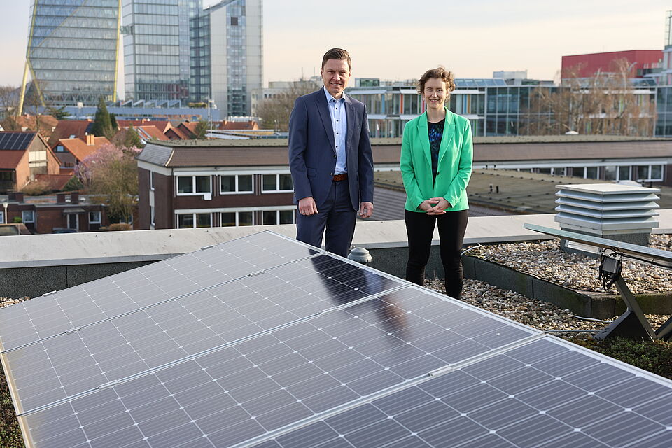 Ein Mann und eine Fra stehen auf einem Flachdach mit einer Photovoltaikanlage.