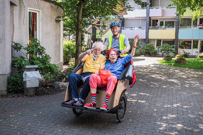 Ein älteres Paar wird mit einer Fahrradrikscha gefahren.