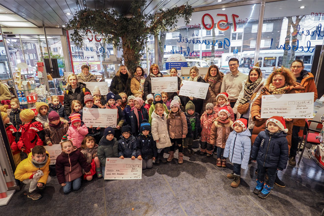 Viele Kita-Kinder und ihre Betreuerinnen freuen sich über große Schecks.